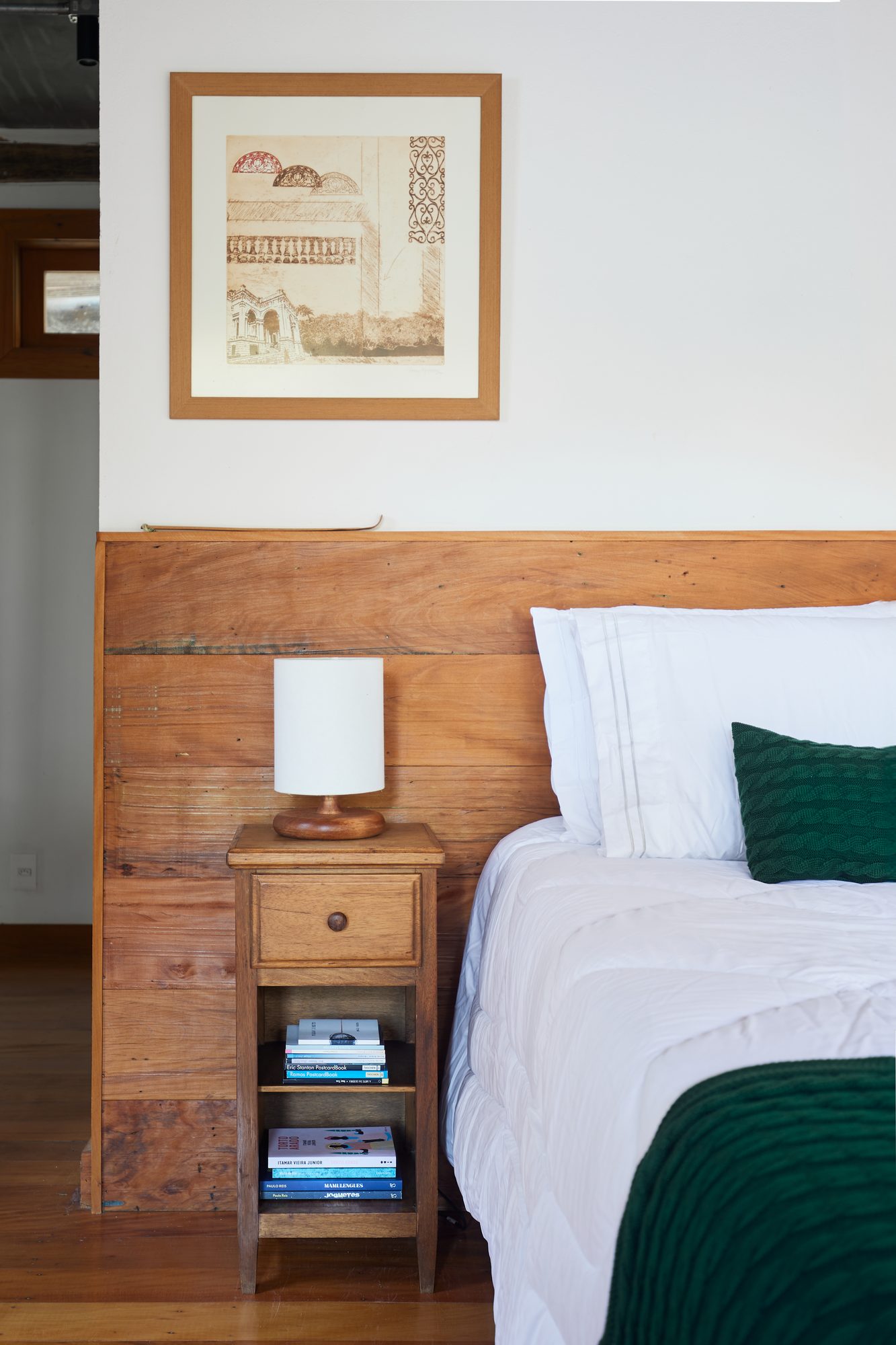 Quarto com cabeceira de madeira, quadro e manta verde