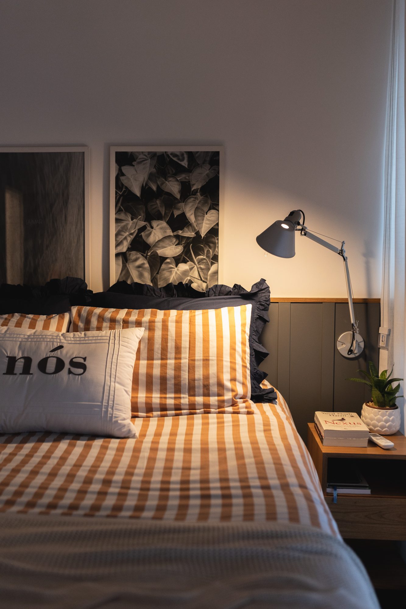 Cama de casal com roupa de cama xadrez e arandela