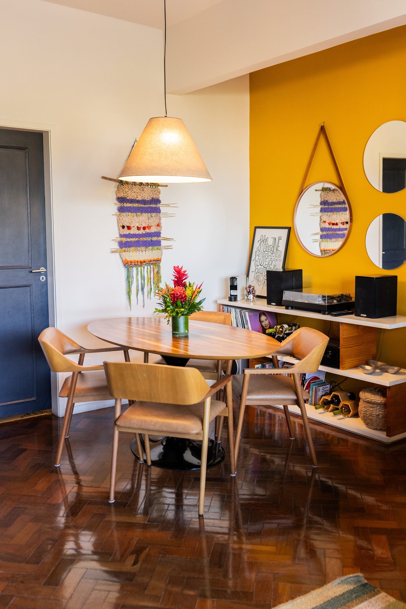 Sala de jantar com parede amarela e luminária pendente