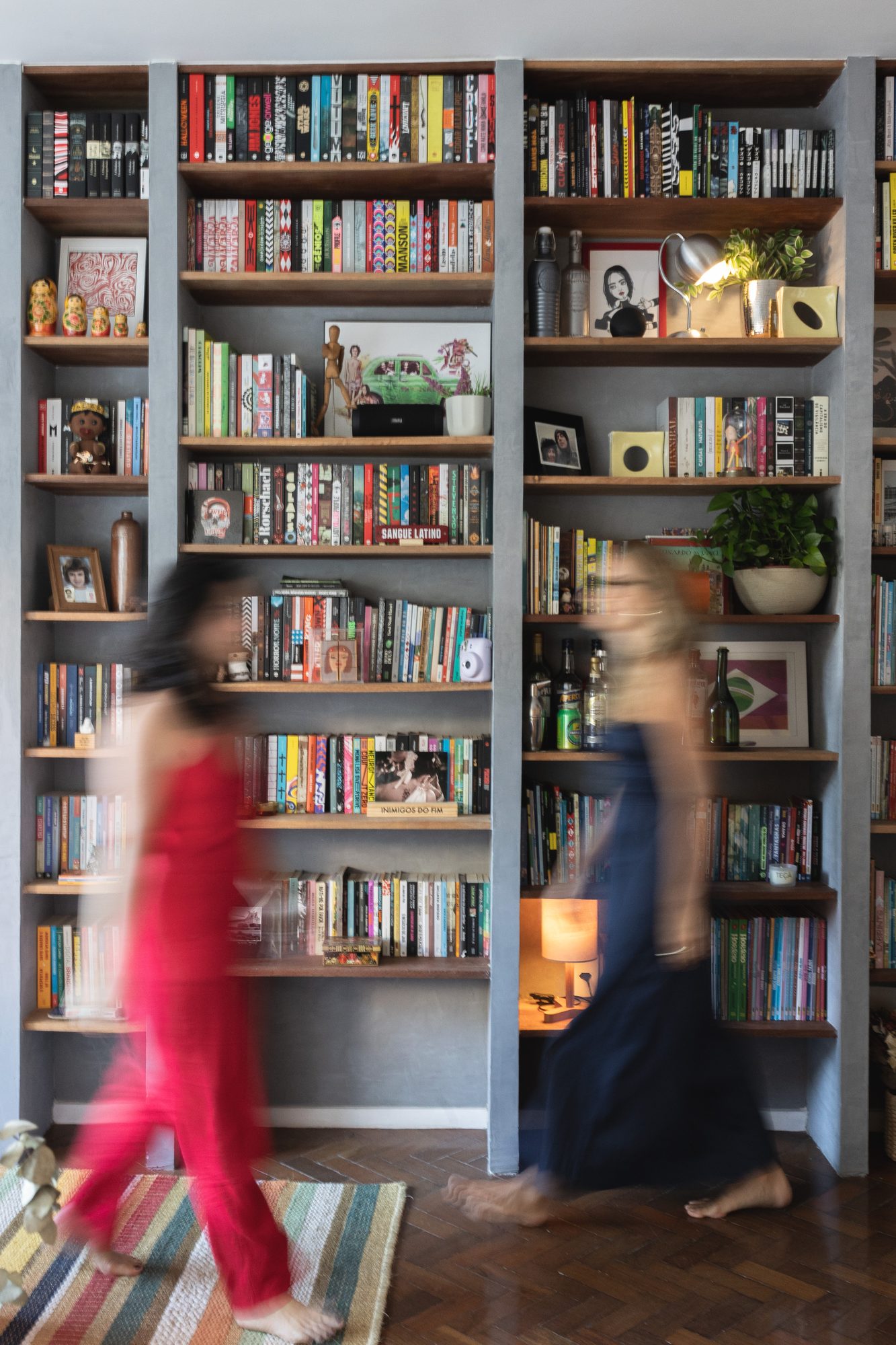 Moradoras passando pela estante de livros