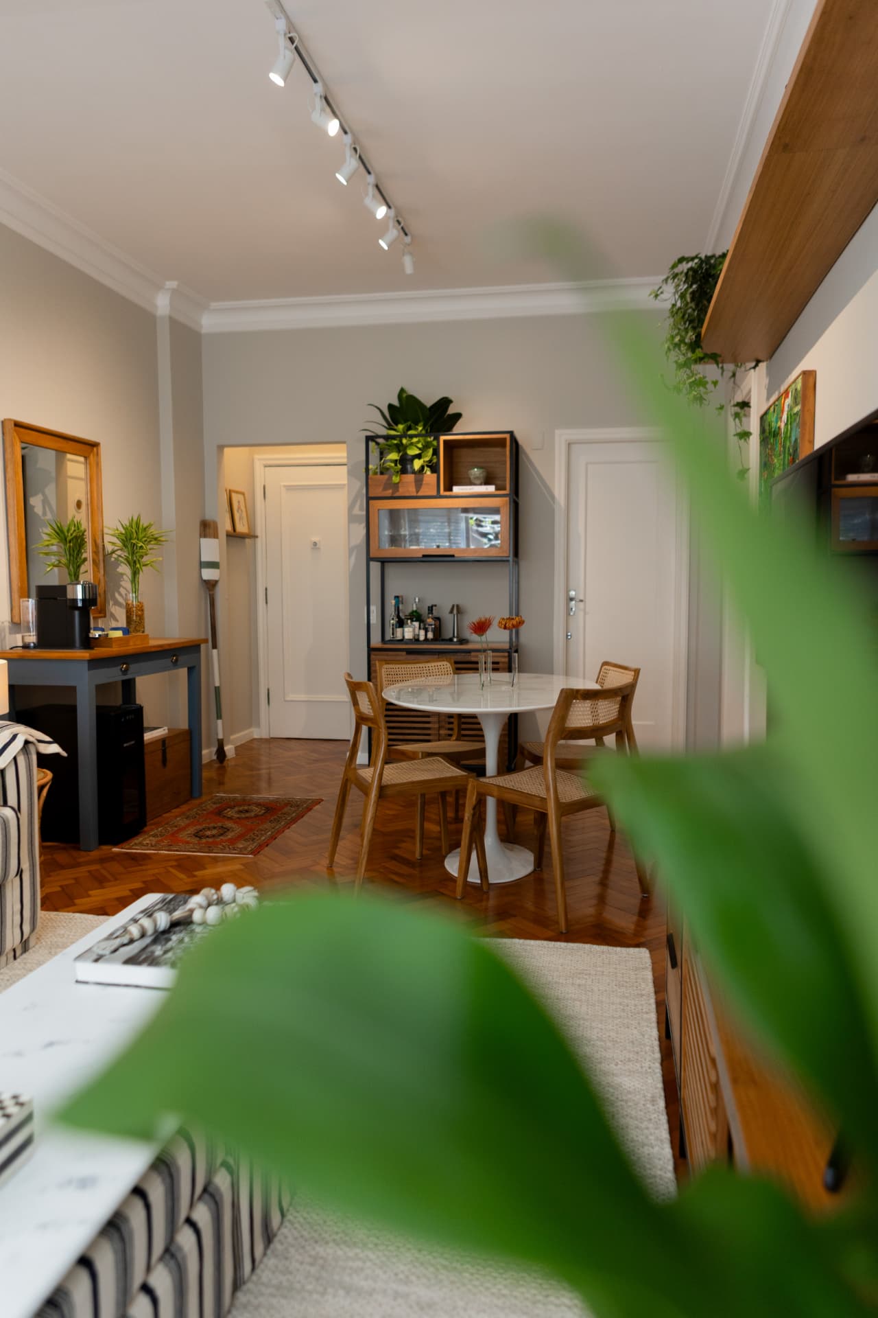 Sala de estar com mesa redonda, marcenaria e folhagens em primeiro plano
