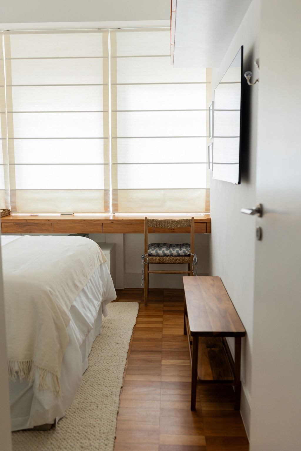 Quarto com bancada de madeira junto à janela e banco lateral